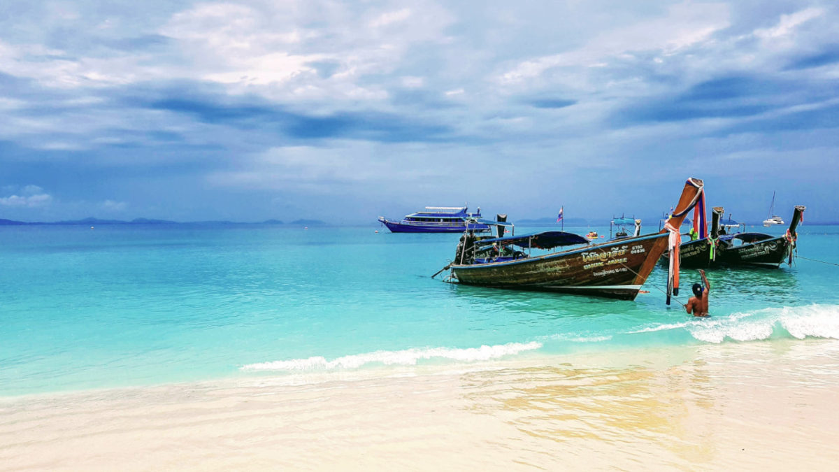 typical Thai taxi boats on the shore of crystal clear turquoise water