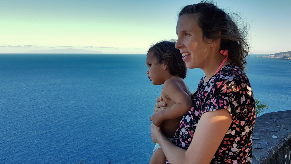 A woman and her son overlooking the ocean, both smiling.